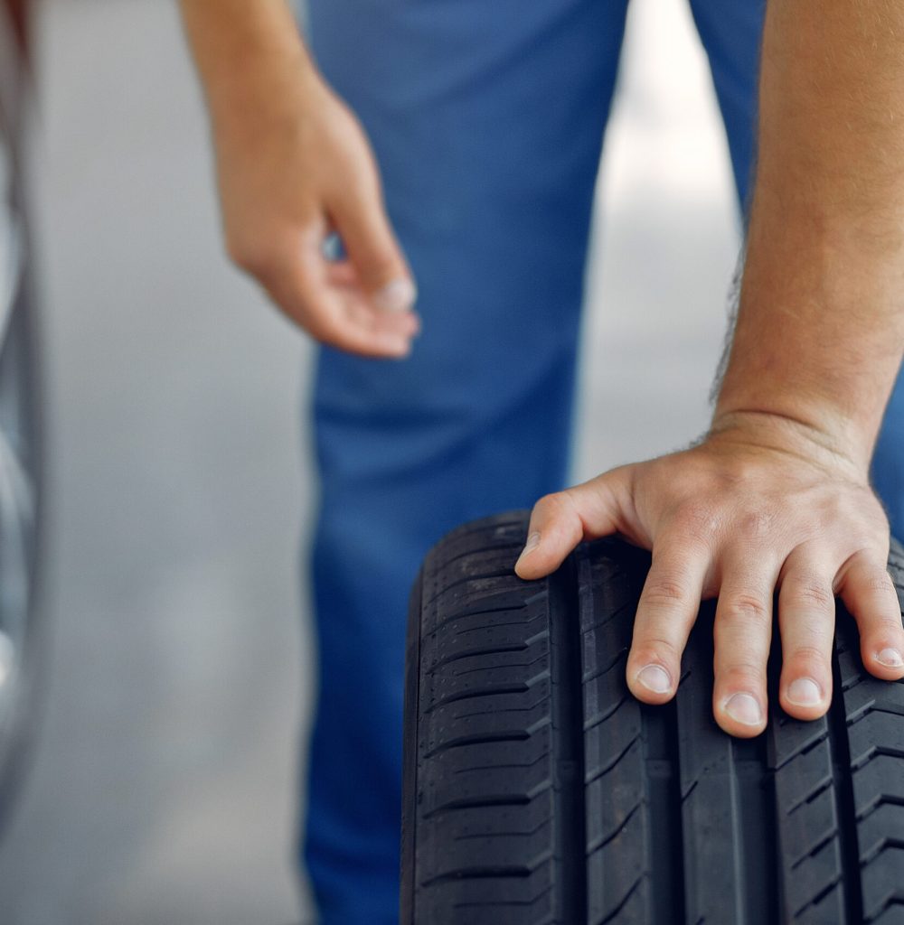 Wrker in a car salon. Expert checks the car. Man in a blue uniform.
